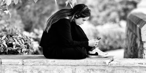 žena so slúchadlami a mobilom počúva angličtinu vonku